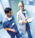 Picture of a female Physician walking down the hall talking to a male Nurse